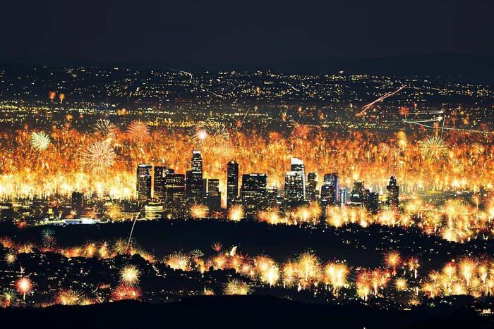 An aerial view of a cityscape illuminated by countless fireworks, creating a beautiful and wonderful display in the night sky.