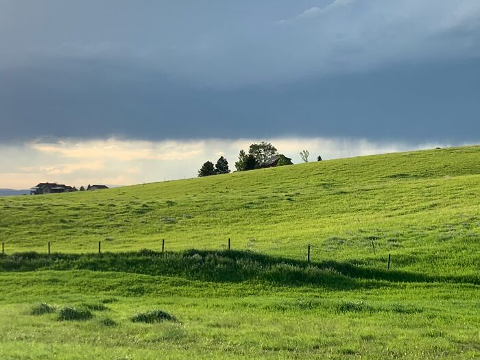 A landscape of green rolling hills and a dark cloudy sky, symbolizing how random things can get people rich.