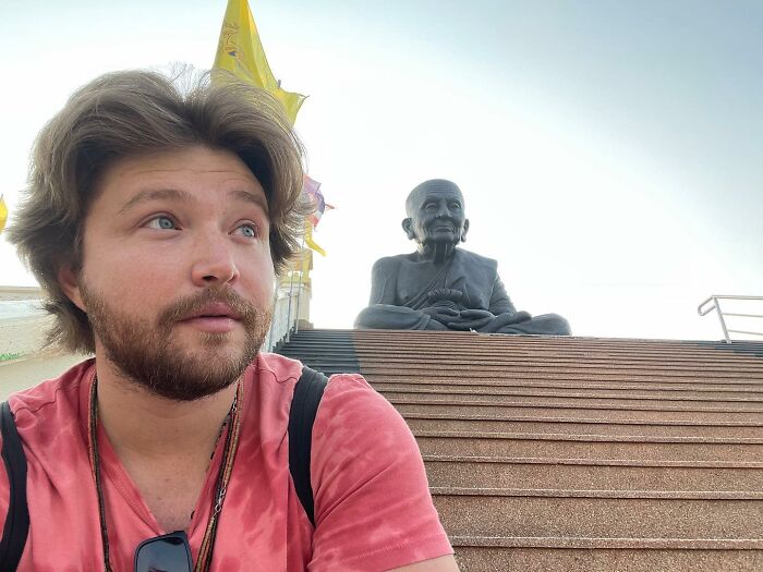 A bearded Disney heartthrob at nearly 40, in front of a large Buddha statue, looking unrecognizable.