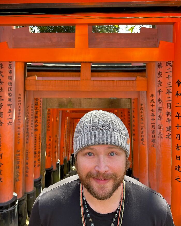 A bearded Disney heartthrob at nearly 40, wearing a beanie, in a tunnel of orange gates, looking unrecognizable.