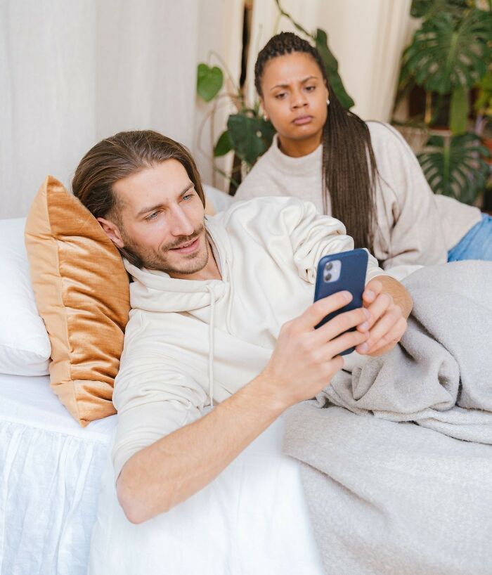 A man looking at his phone while a woman looks on with concern, showing friendships that fell apart.