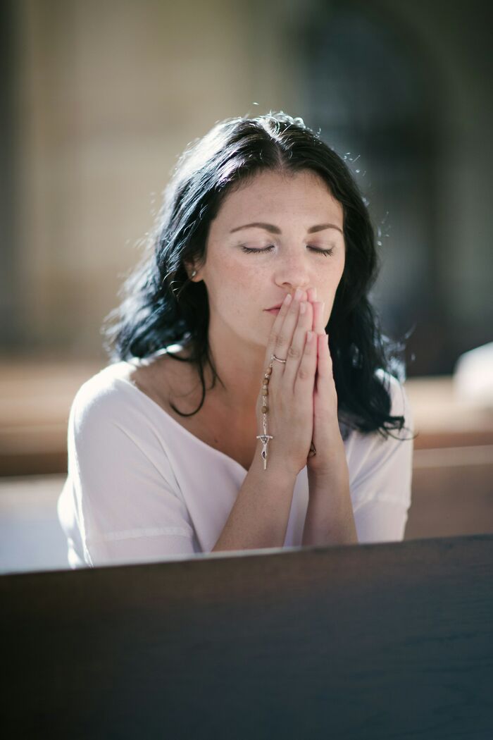 Woman praying with a rosary, contemplating friendships that fell apart after years of being close.