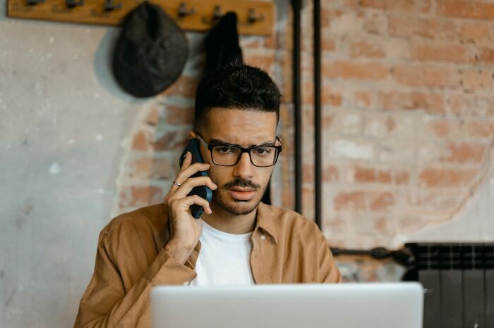 Man on the phone with a laptop, reflecting on friendships that fell apart after years of being close.