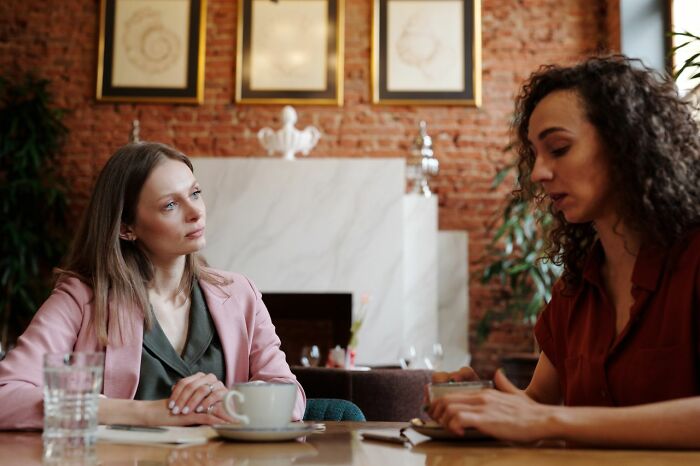 Two women talking intently over coffee, one listening, the other speaking, discussing why friendships fell apart.