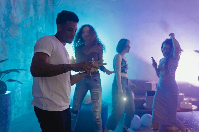Four friends dancing and enjoying themselves at a party, illuminated by blue light.