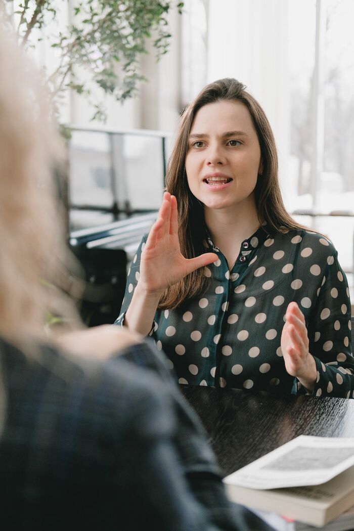 A woman gesturing while talking, discussing friendships that fell apart after years of being close.
