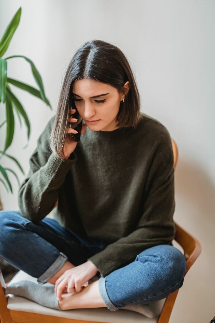 A woman on the phone, her serious expression suggesting friendships falling apart after years of being close.