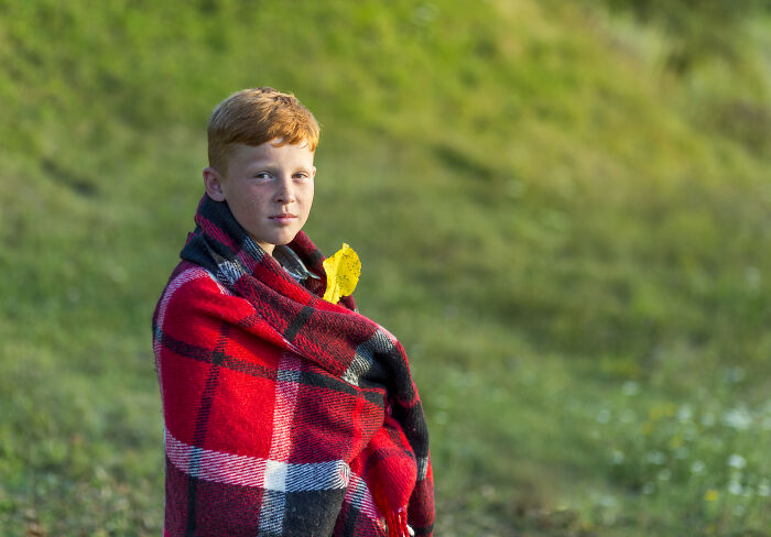 A young boy wrapped in a red blanket outdoors, illustrating a common name that many find difficult to pronounce. A young boy wrapped in a red blanket outdoors, illustrating a common name that many find difficult to pronounce.