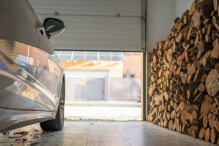 Man's home and land, free of HOA rules, with a car parked in a garage next to a stack of firewood. Man's home and land, free of HOA rules, with a car parked in a garage next to a stack of firewood.