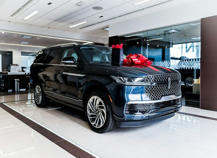 A luxurious dark SUV with a red bow, showing the wild moments of those who worked for the rich.