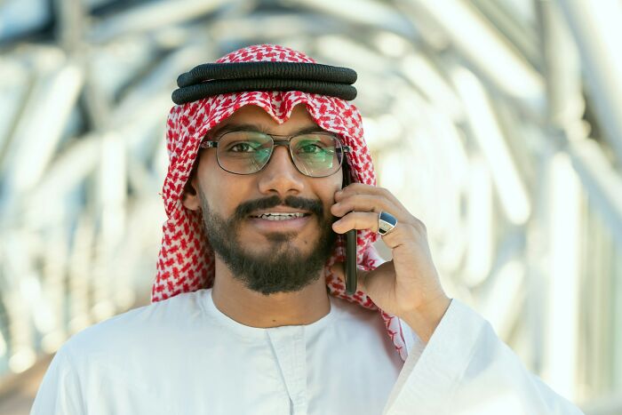 A man in traditional attire on a phone, representing the rich and their unique experiences.