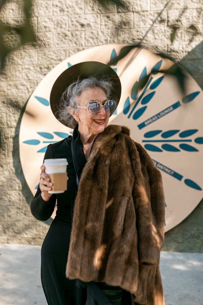 An older woman with sunglasses and a fur coat, holding coffee, depicting wild moments shared by people who worked for the rich.