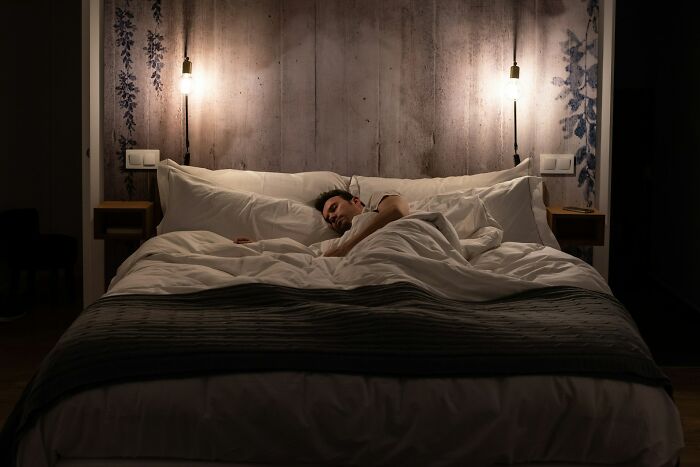 A man sleeping in a large bed with white bedding, demonstrating wild moments that left people speechless.