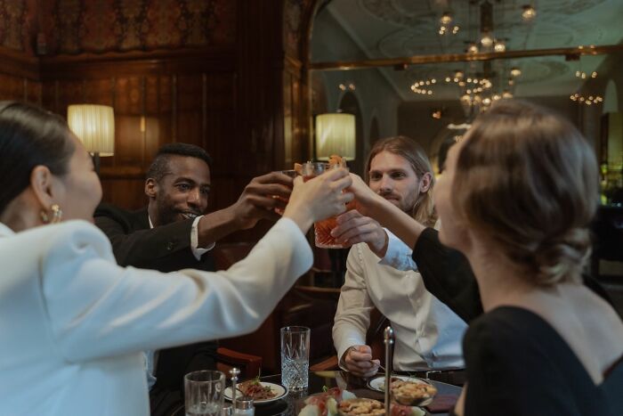 Friends toasting drinks at a fancy restaurant. People who worked for the rich share wildest moments.