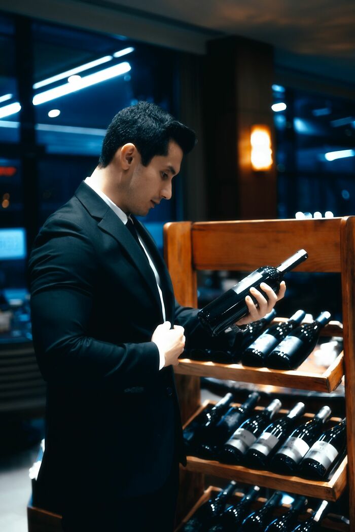 A man in a suit looks at a bottle of wine. Moments that left people speechless from working for the rich.