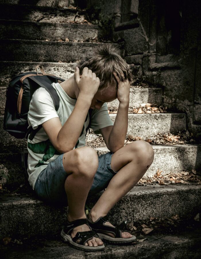 A young boy sitting sadly on stone stairs, highlighting interesting neighbors.