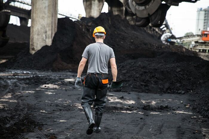 A worker in a hard hat walks away from large piles of coal, suggesting a legal dispute related to the industry or court case stories.