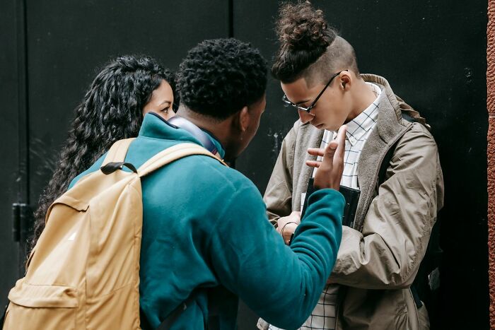 Three young people discuss, one pointing at something, illustrating potential real-life court case stories.
