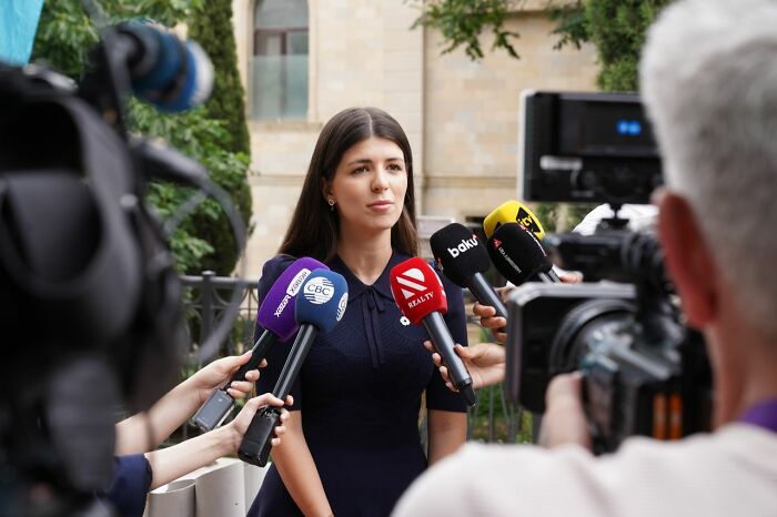 A woman giving an interview to multiple reporters, representing one of the many court case stories.