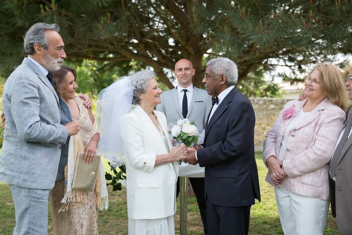 An elderly couple getting married outdoors, surrounded by family, illustrating a heartwarming court case story.