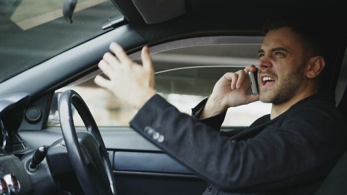 A man in a car, visibly upset and talking on his phone, an example of a dramatic court case story.