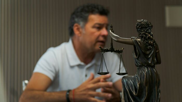 A man with grey hair talks next to a Statue of Justice, representing various court case stories.