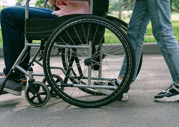 A person in a wheelchair being pushed, representing challenges faced during midlife crises.