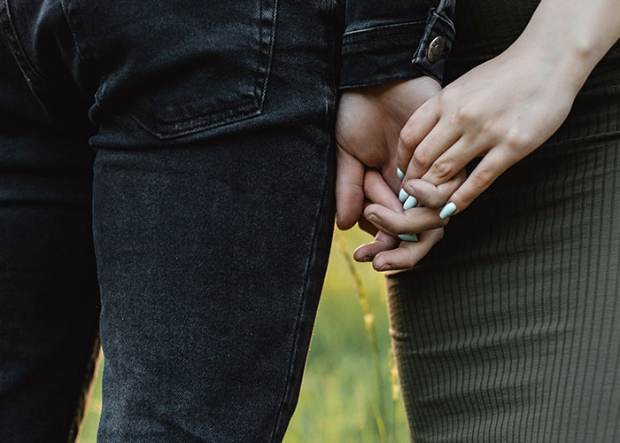 Two people holding hands, a common action that may be part of a cringe midlife crisis.