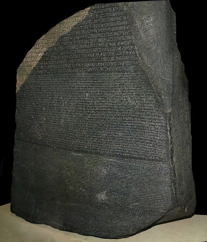 The Rosetta Stone, a large, dark historical artifact with ancient scripts carved into its surface.