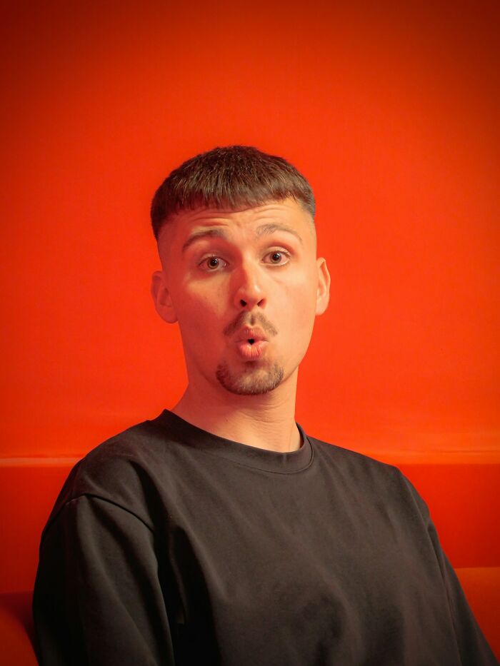A man with a short haircut and beard making a surprised face against an orange background, illustrating scary true stories.