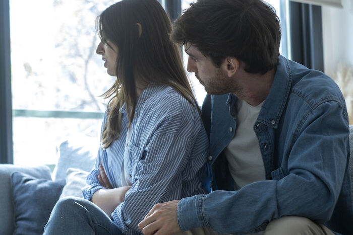 A woman with her arms crossed, turning her back to a man, illustrating relationship red flags and mental health struggles.