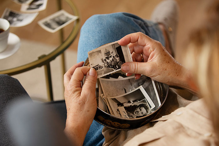 Elderly hands carefully sorting through old black and white photos, revealing signs from the universe and past memories.