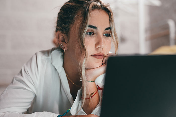A woman at her laptop, thinking about the coworker who used her number to ask if she is married or single.