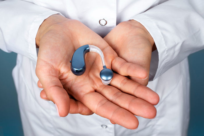 A person holding a blue and clear hearing aid in their palms, highlighting the device before it was destroyed. A person holding a blue and clear hearing aid in their palms, highlighting the device before it was destroyed.