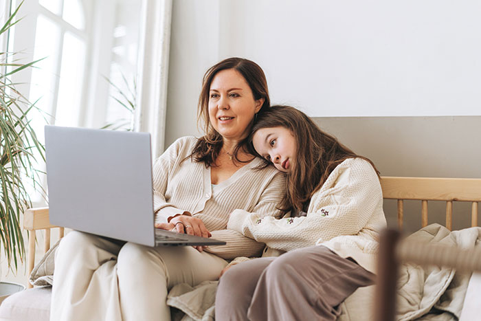 A woman and a young girl sit on a couch, looking at a laptop screen. The woman adopted her sister's baby. A woman and a young girl sit on a couch, looking at a laptop screen. The woman adopted her sister's baby.