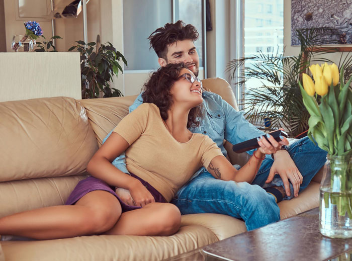 A happy couple on a couch, showing the dynamics of a woman's infertility and her half-sis's taunts.