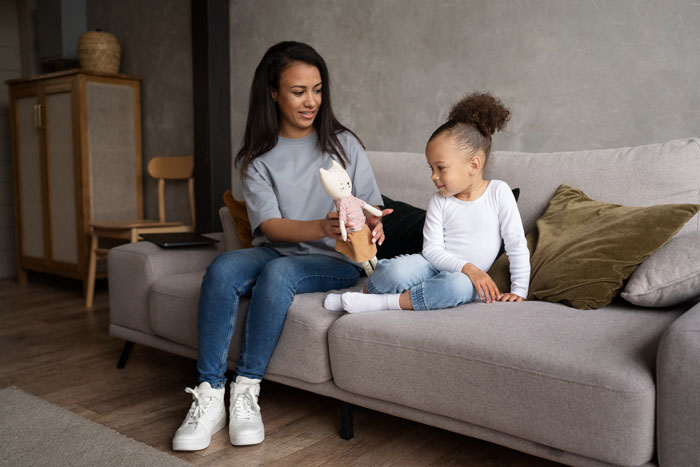 A woman and a young girl, possibly a half-sister and her baby, sitting on a couch, related to infertility
