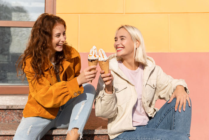 Two young women, laughing and enjoying ice cream, illustrate the narrative of a half-sister's taunts over infertility.