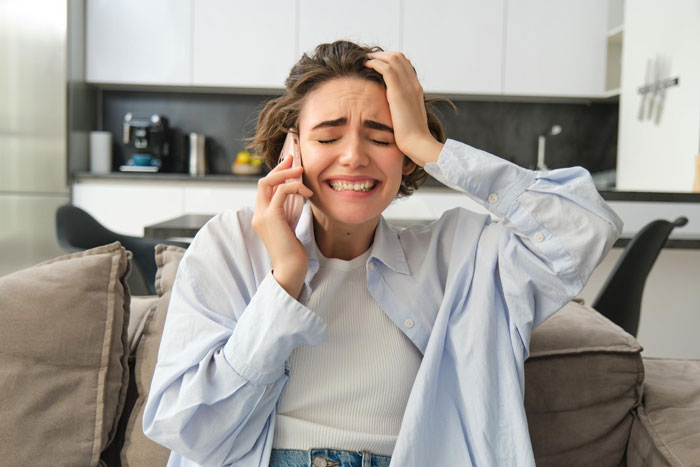 A distraught woman on the phone, conveying the emotional impact of infertility taunts from her half-sis.