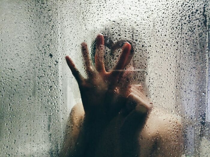 A hand drawing a heart on a steamy shower door, reflecting interesting neighbors.