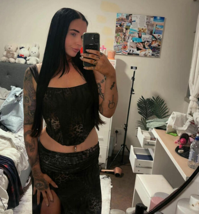 A devastated mom takes a selfie in a mirror, showing her full body and tattoos. A devastated mom takes a selfie in a mirror, showing her full body and tattoos.