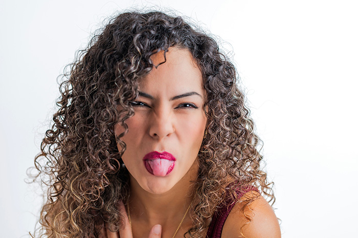 A woman with curly hair makes a disgusted face, sticking out her tongue, representing the conflict with spoiled SIL. A woman with curly hair makes a disgusted face, sticking out her tongue, representing the conflict with spoiled SIL.
