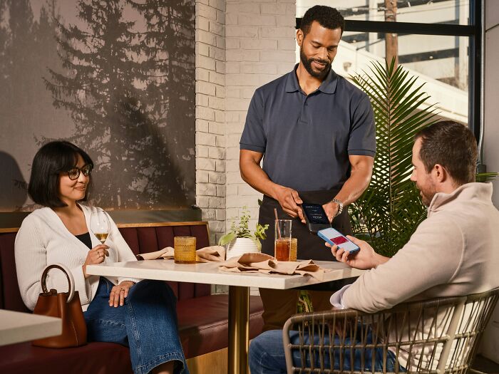 A man paying at a restaurant with his phone, revealing a secret about his finances.