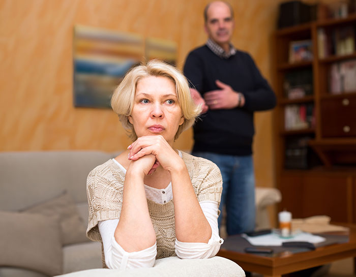 A serious woman with a man in the background, depicting a woman's hopes for motherhood through grandkids. A serious woman with a man in the background, depicting a woman's hopes for motherhood through grandkids.