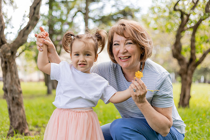 A happy grandma and grandchild outdoors, illustrating a woman experiencing motherhood through grandkids. A happy grandma and grandchild outdoors, illustrating a woman experiencing motherhood through grandkids.