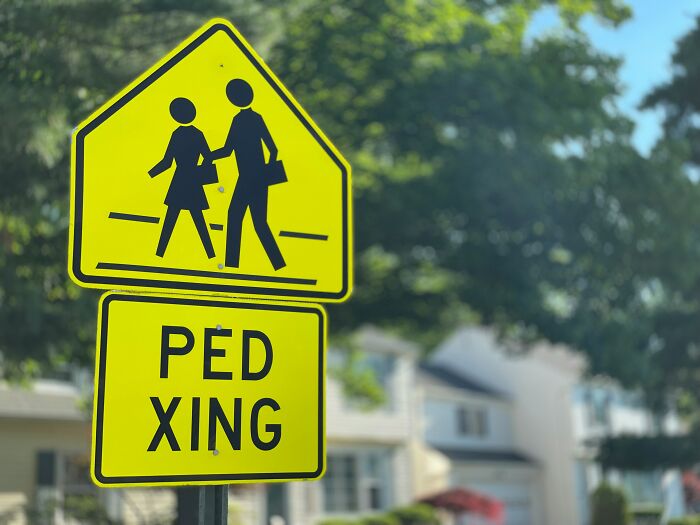A crosswalk sign in America with a Ped Xing warning, highlighting a detail that newcomers might find surprising.