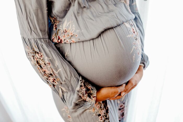 A pregnant woman cradling her belly, reflecting a personal side often affected by workplace dramas.