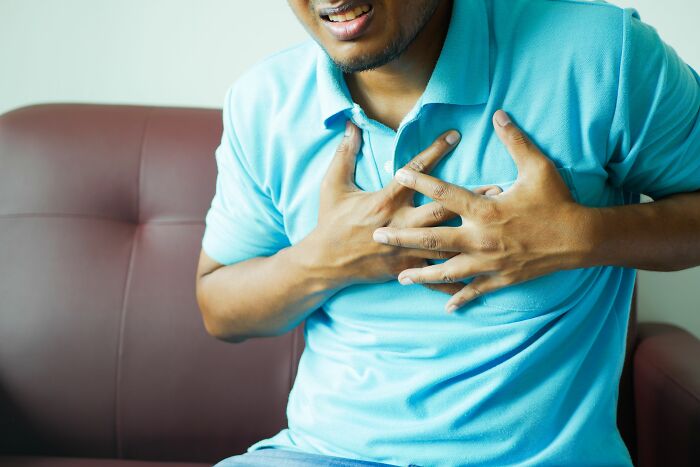 A man clutching his chest in pain, symbolizing the stress and unhinged workplace dramas.