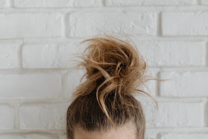 A messy bun hairstyle, often associated with casual or stressful work, perfect for workplace dramas