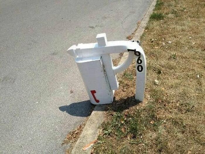 A white mailbox with the number 660, bent and twisted, showcasing summer melting and ruining.
